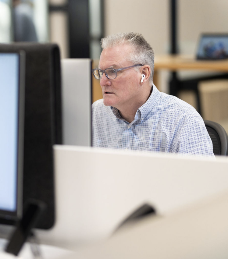 Man working at a desk on the computer with headphones in